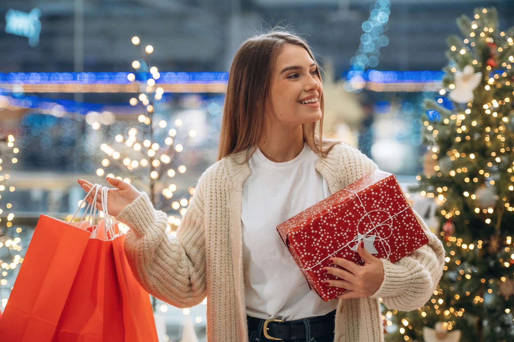 Una mujer camina por un centro comercial cargada de regalos.
