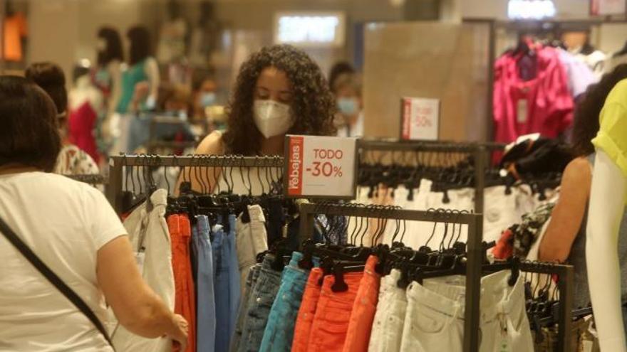 Dos mujeres miran las prendas en una tienda de ropa.