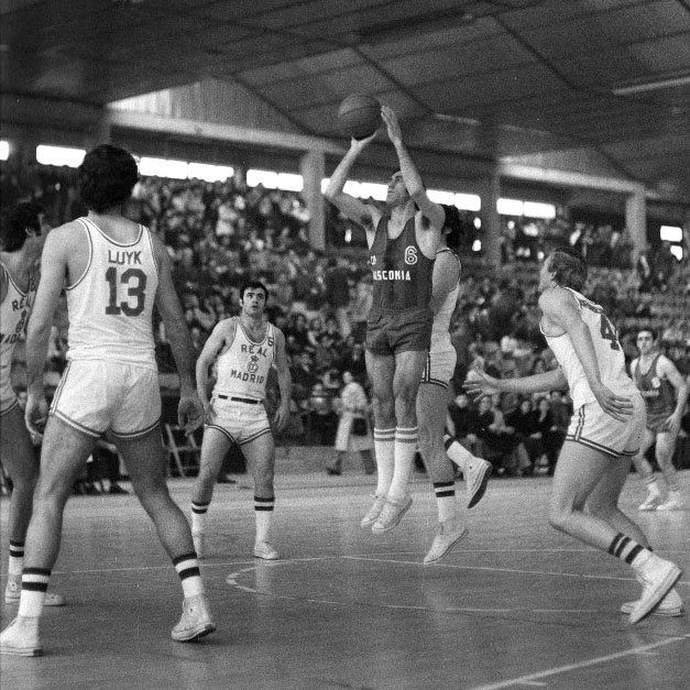 &#039;Tacha&#039; Lázaro lanza a canasta rodeado de cinco jugadores del Real Madrid, con Juan Pinedo observando al fondo: &#039;carácter Baskonia&#039; que aún perdura.