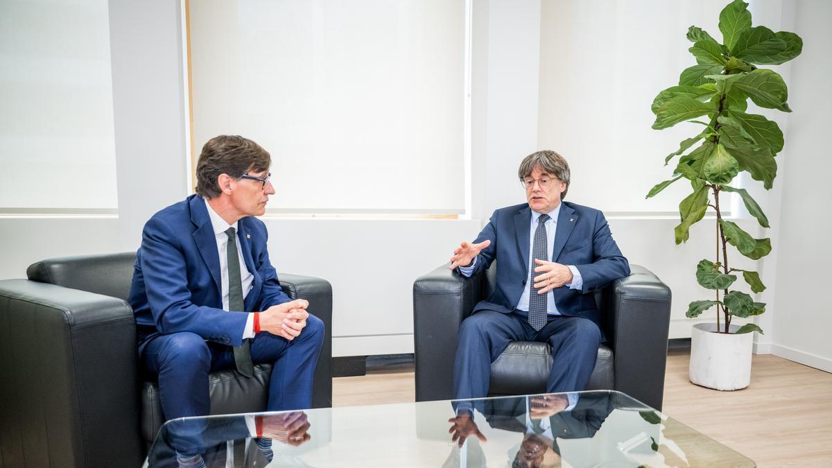 El presidente de la Generalitat, Salvador Illa (i), saluda al presidente de Junts per Catalunya, Carles Puigdemont (d), durante su reunión en Bruselas.