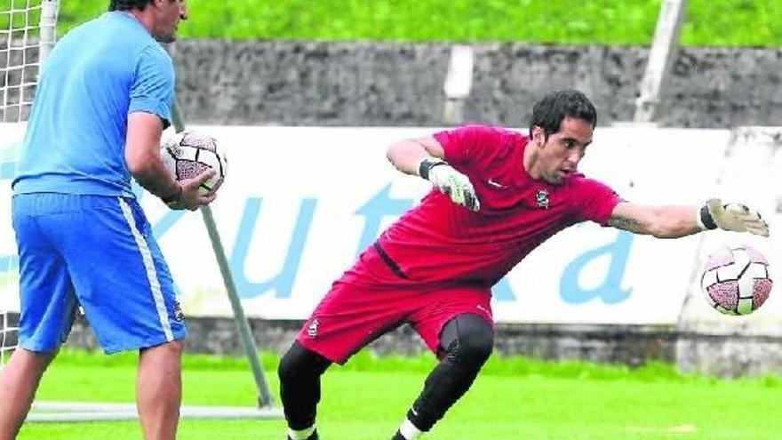 Claudio Bravo detiene un balón durante el entrenamiento de ayer en Zubieta, junto al preparador de porteros Roberto Navajas.