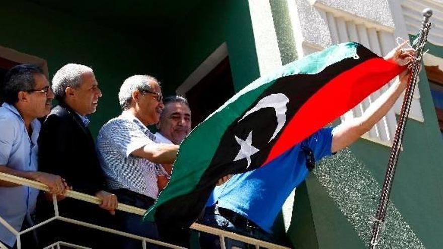 Manifestantes libios izan la bandera tricolor del Consejo Nacional de Transición tras retirar la hasta ahora bandera nacional libia.