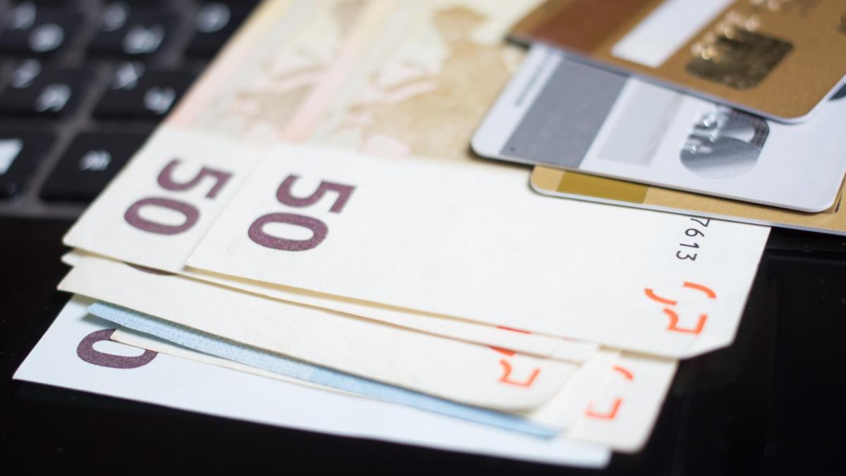 Billetes de euro y tarjetas bancarias sobre el teclado de un ordenador.