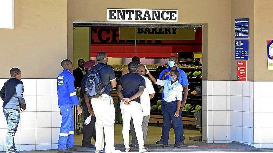 Un trabajador mide la temperatura de los clientes antes de que entren en una tienda en Harare, Zimbabue. Foto: Efe