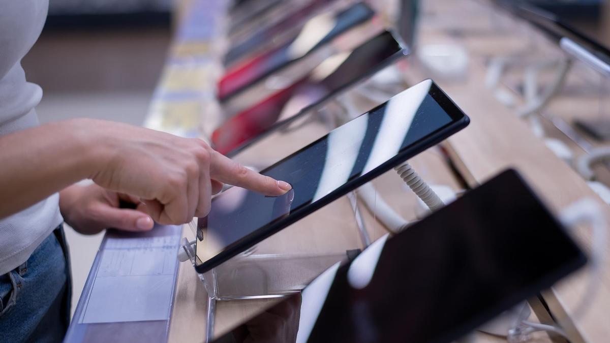 Una persona toca la pantalla táctil de un móvil en una tienda.