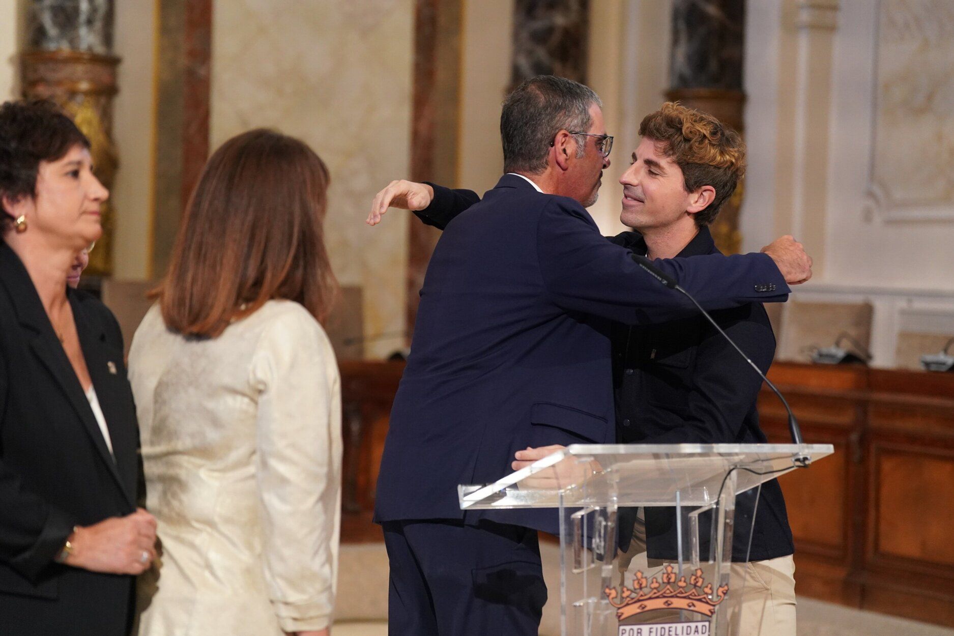 El edil de Cultura, Jon Insausti, abraza al alcalde de Donostia, Eneko Goia, tras la comparecencia en la que ha anunciado su adiós
