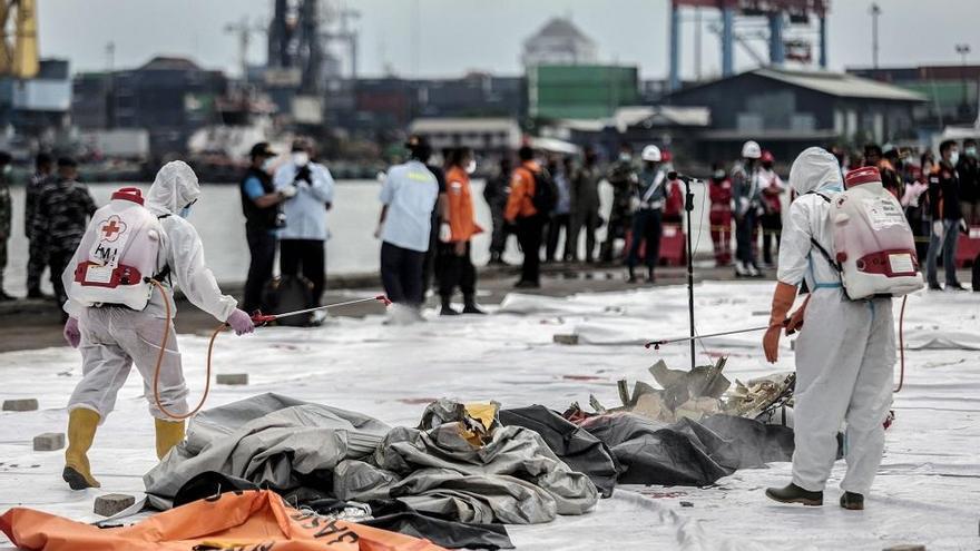 Personal sanitario desinfecta las bolsas con restos humanos.
