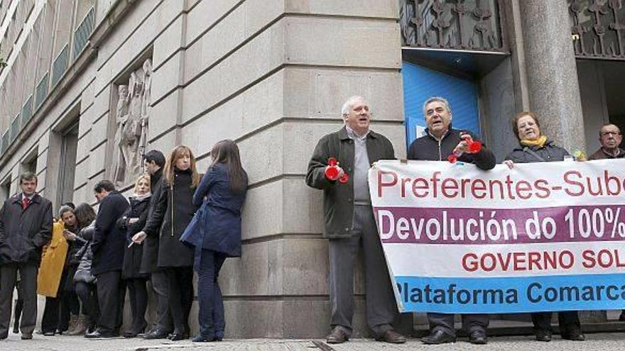 Un grupo de clientes afectados por el fraude de las preferentes (dcha) se manifiesta para exigir su dinero en un lado de la central de Novagalicia, mientras los trabajadores de la oficina se concentran en el lateral de la oficina, para protestar por el ER