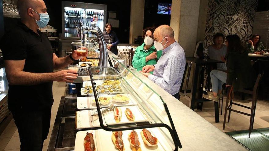 Clientes con mascarilla en la barra del bar Guria