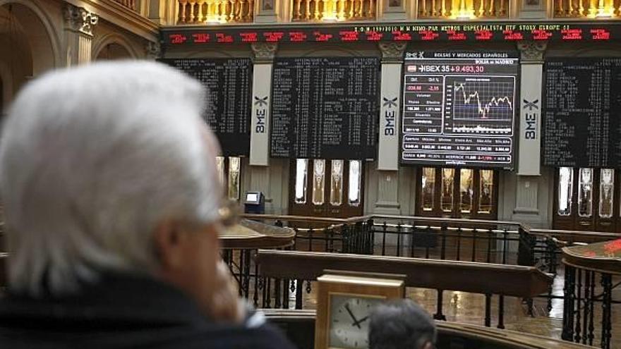 Varios operadores de la Bolsa de Madrid, ante el panel del ÍBEX 35.