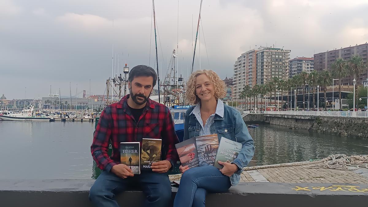 Unai Antolín y Ainhoa Urberuaga posan con algunas de sus novelas en el puerto pesquero de Santurtzi.