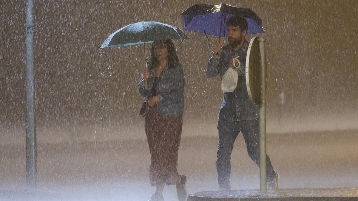 Dos personas, bajo la tormenta que cayó este sábado a la noche en Pamplona.
