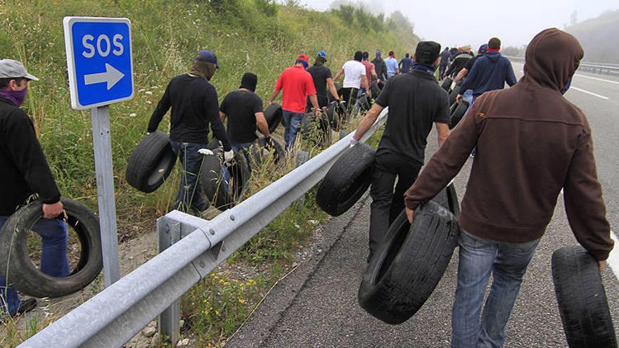 Varios mineros transportan neumáticos usados a los que luego prenderán fuego para cortar una carretera.