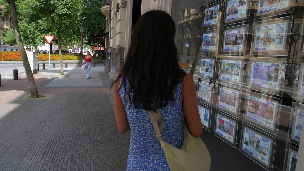 Una joven observa el escaparate de una inmobiliaria de Bilbao.