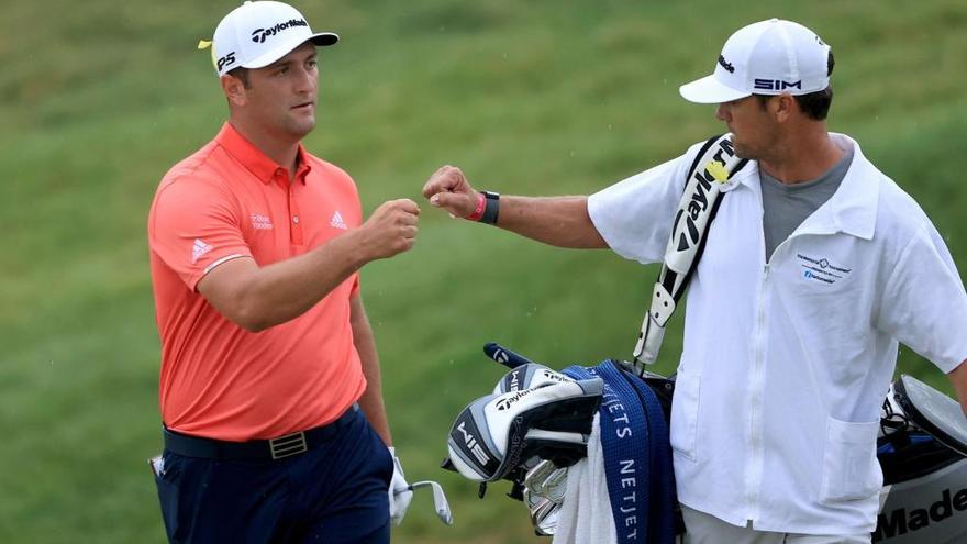 Jon Rahm celebra con su caddie Adam Hayes el chip decisivo que embocó en el 16