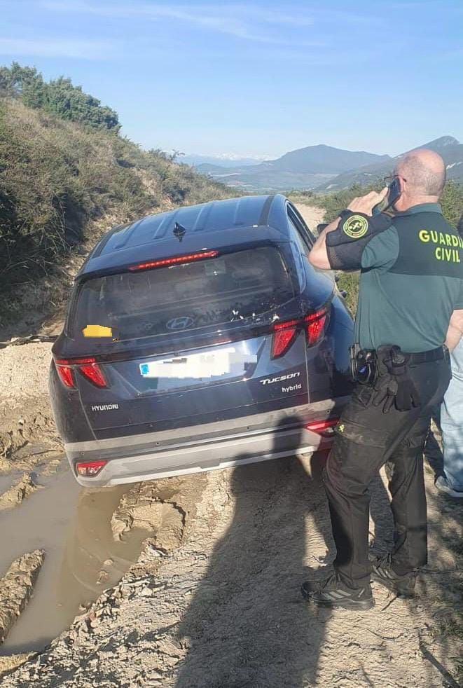 Un agente de Guardia Civil junto al vehículo atrapado en el barro.