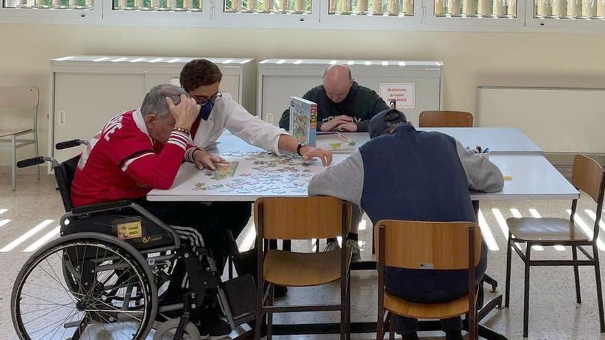 Mateo Bartollini ayuda a completar un puzzle con uno de los pacientes.