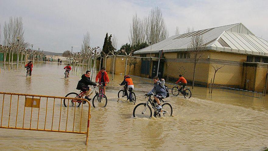 Varios niños cruzan el agua rebosada del Arga a su paso por Falces, en la inundación de 2007.