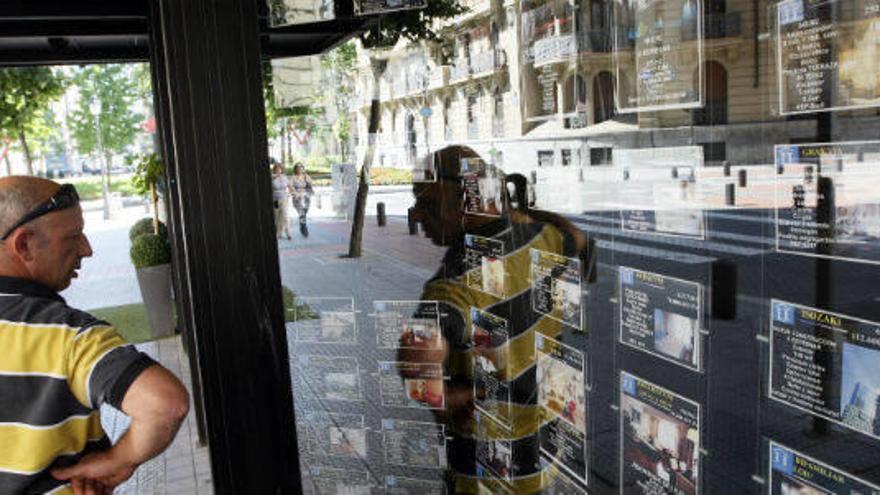 Una pareja observa el escaparate de una inmobiliaria en Bilbao.