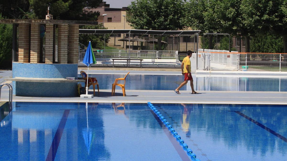 Un socorrista pasando por delante de una de las piscinas de verano en la Ribera en una foto de archivo.