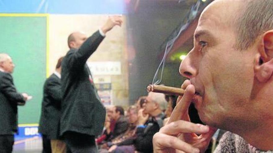 Un aficionado a la pelota fuma un puro durante un partido en el frontón de Bergara.