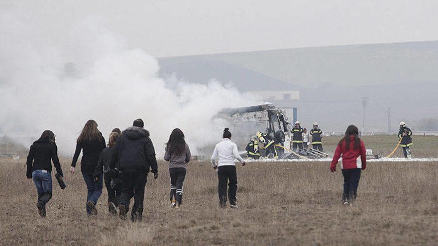 Los bomberos acaban de apagar el incendio del avión simulado, mientras se aproximan los pasajeros.