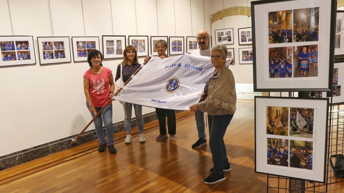 Miembros de Anaiarte, con la bandera de la asocación, en la muestra fotográfica que recoge los 25 años de la tamborrada.