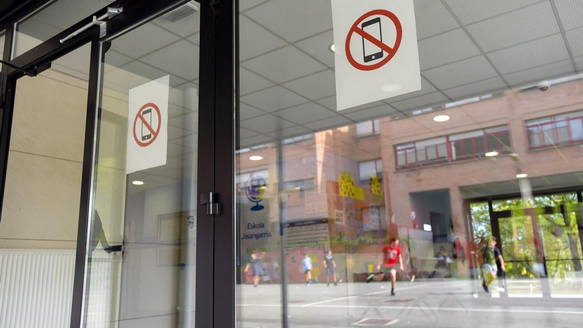 Carteles colocados en un centro educativo guipuzcoano que indican la prohibición de hacer uso del móvil en el recinto escolar.