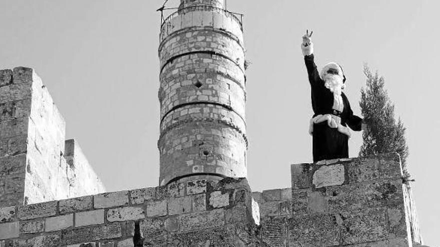 Un palestino disfrazado de Papá Noel saluda desde la muralla de la ciudad vieja de Jerusalén (Israel).