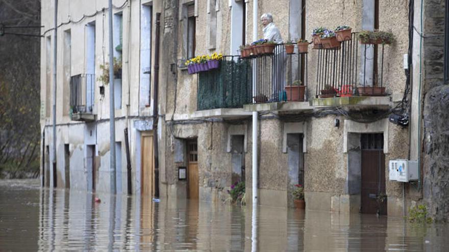 Una mujer observa el efecto de la riada en la calle Magdalena de Pamplona, junto al Arga.