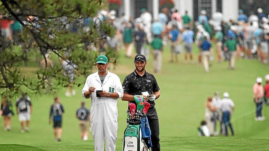 Jon Rahm espera junto a su caddie Adam Hayes el momento de golpear en la calle del hoyo 1 ayer en el Augusta National. Foto: Afp