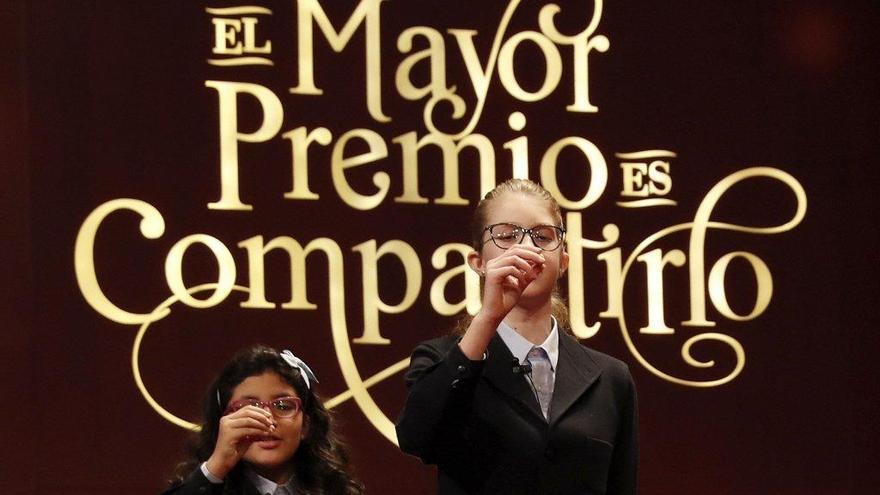 Dos niñas de San Ildefonso cantan uno de los premios de la lotería de Navidad.