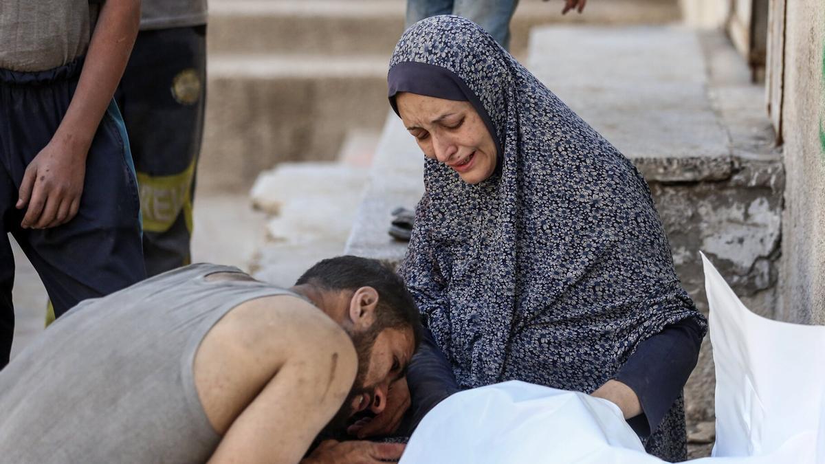 Dos personas lloran la pérdida de un ser querido en Gaza.
