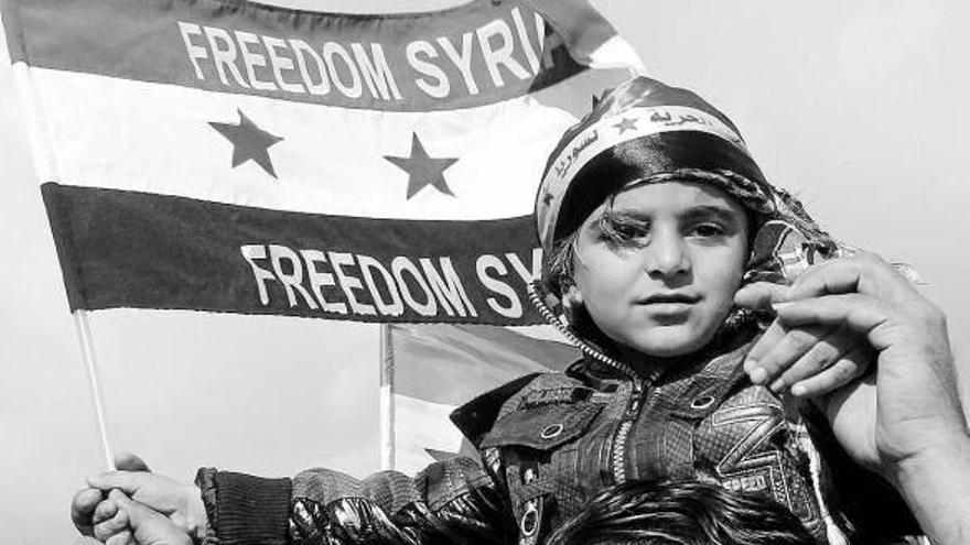 Un niño sostiene una bandera en una manifestación por la liberación de Siria.