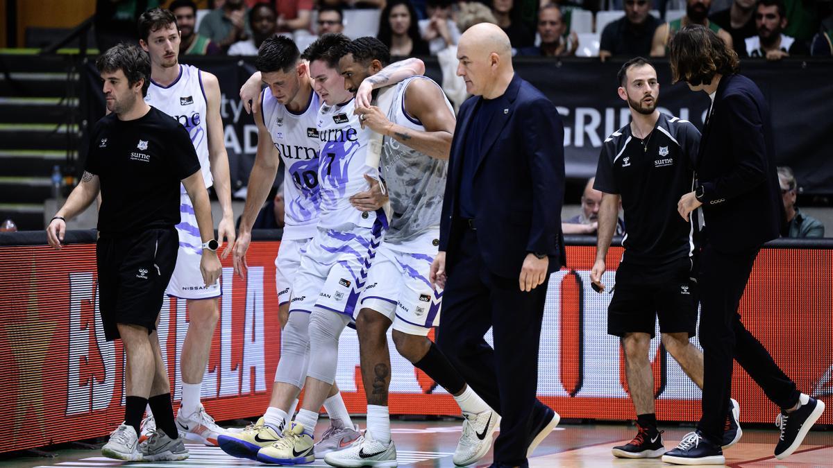 Jaworski abandona la cancha del Olimpic ayudado por dos compañeros.