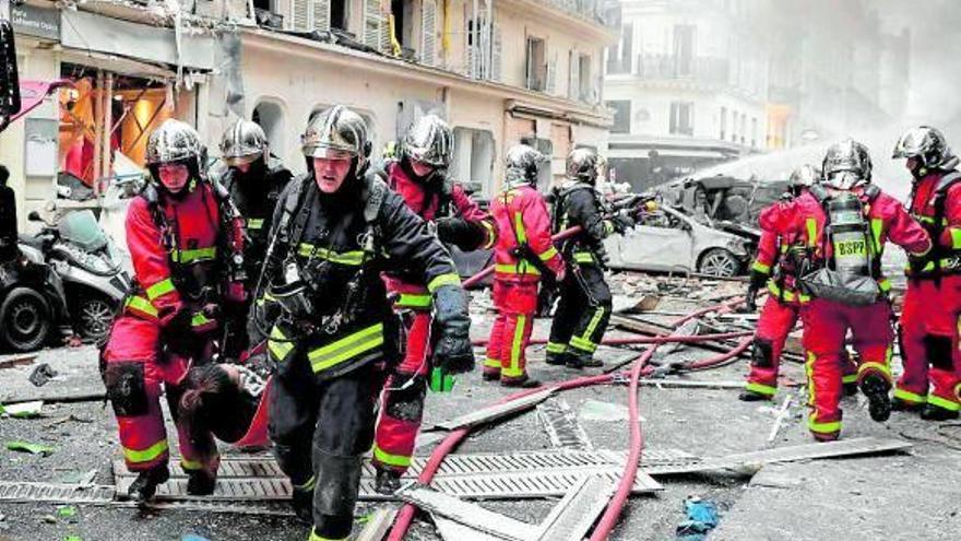 Bomberos franceses evacuan a una mujer herida en la explosión de una panadería.
