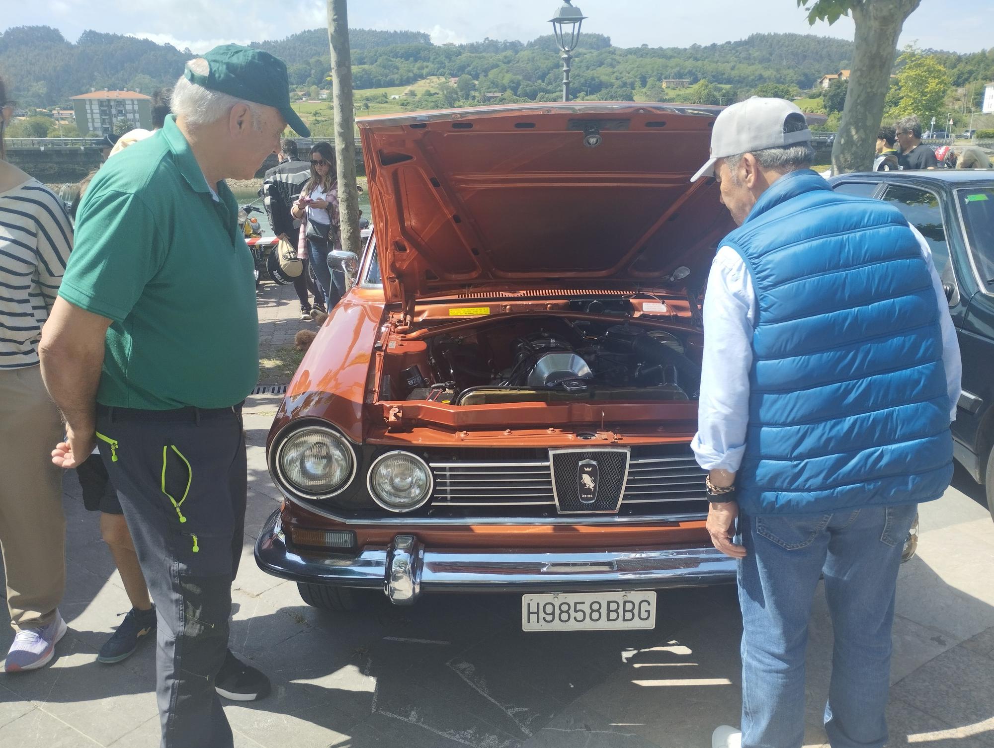 Muchos de los coches expuestos abren sus capós.