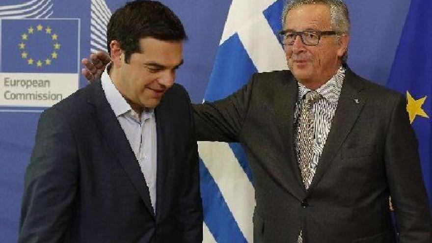 El presidente de la Comisión Europea, Jean-Claude Juncker, da una palmada en la espalda del primer ministro griego, Alexis Tsipras.