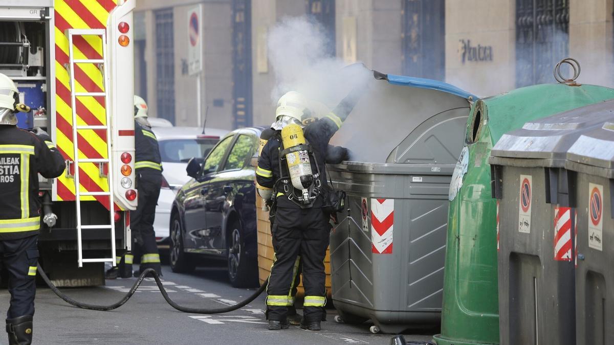 Un bombero apaga un incendio en un contenedor producido en otra ocasión