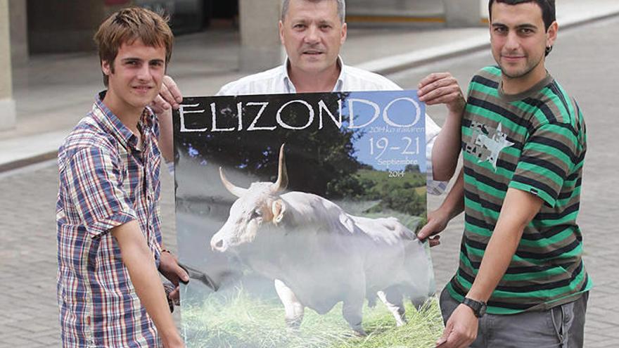 El ganadero Álvaro Garde, Patxi Aranguren y Ion Elizetxe posan con el cartel del concurso de este año, con una fotografía de Xavier Landa.