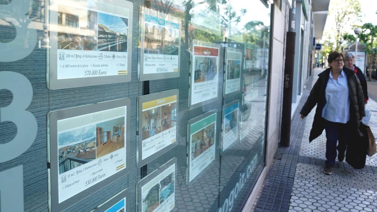 Dos mujeres junto al escaparate de una inmobiliaria donostiarra que anuncia pisos en venta y alquiler.