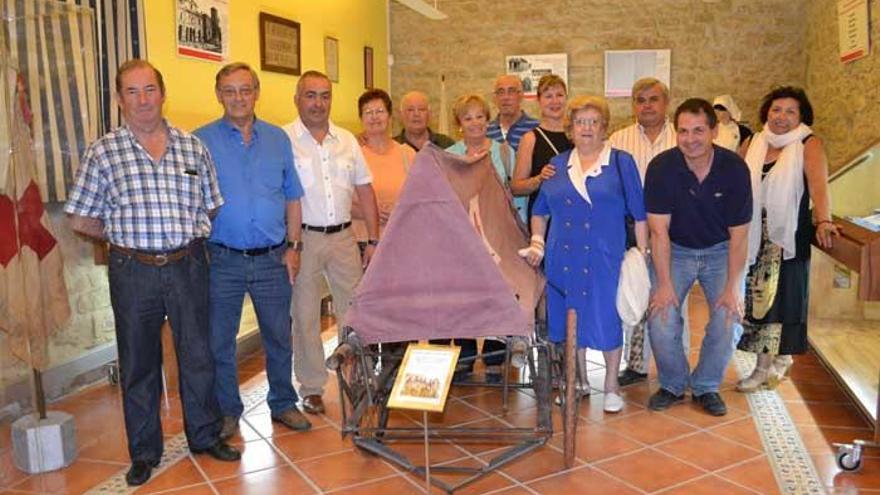Un grupo de voluntarios de Cruz Roja, junto a una antigua camilla que puede verse en la exposición.