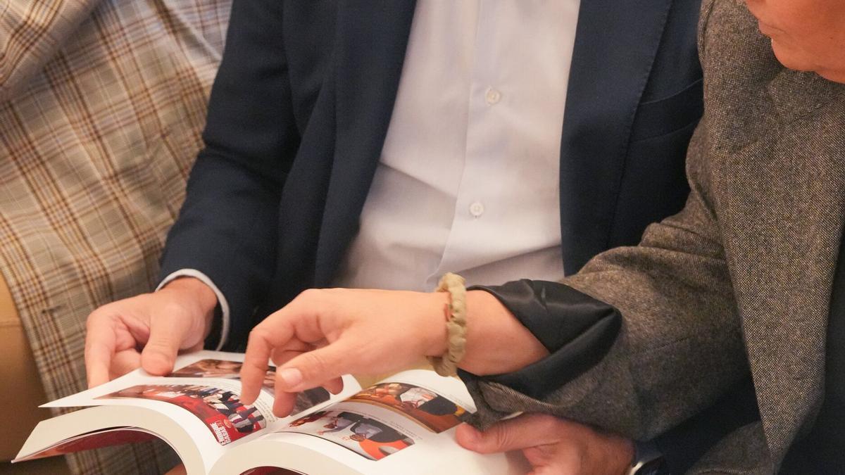 Dos personas consultan varias fotografías en el libro de memorias de Jesús Eguiguren