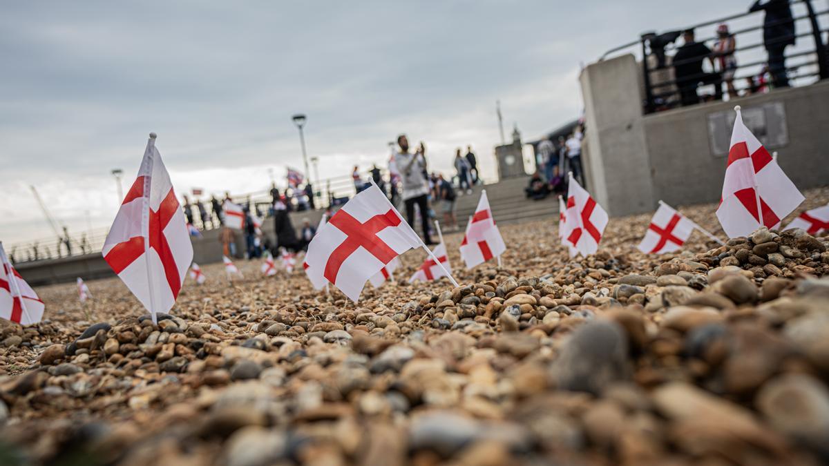 Pequeñas banderas de San Jorge plantadas en la playa de piedra de Dover, al otro lado del canal de Calais.