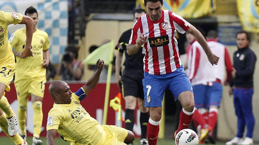 El delantero del Atlético de Madrid Adrián López (d) conduce el balón ante la entrada del centroampista del Villarreal CF Marcos Senna