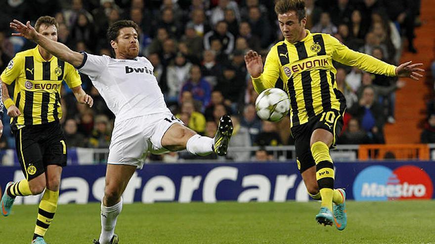 Xabi Alonso golpea el balón ante el centrocampista del Borussia Dortmund Mario Götze.