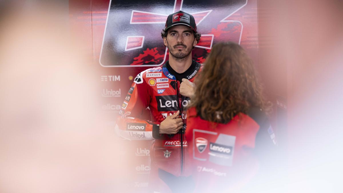 Francesco Bagnaia se ata el mono en el box de Ducati.