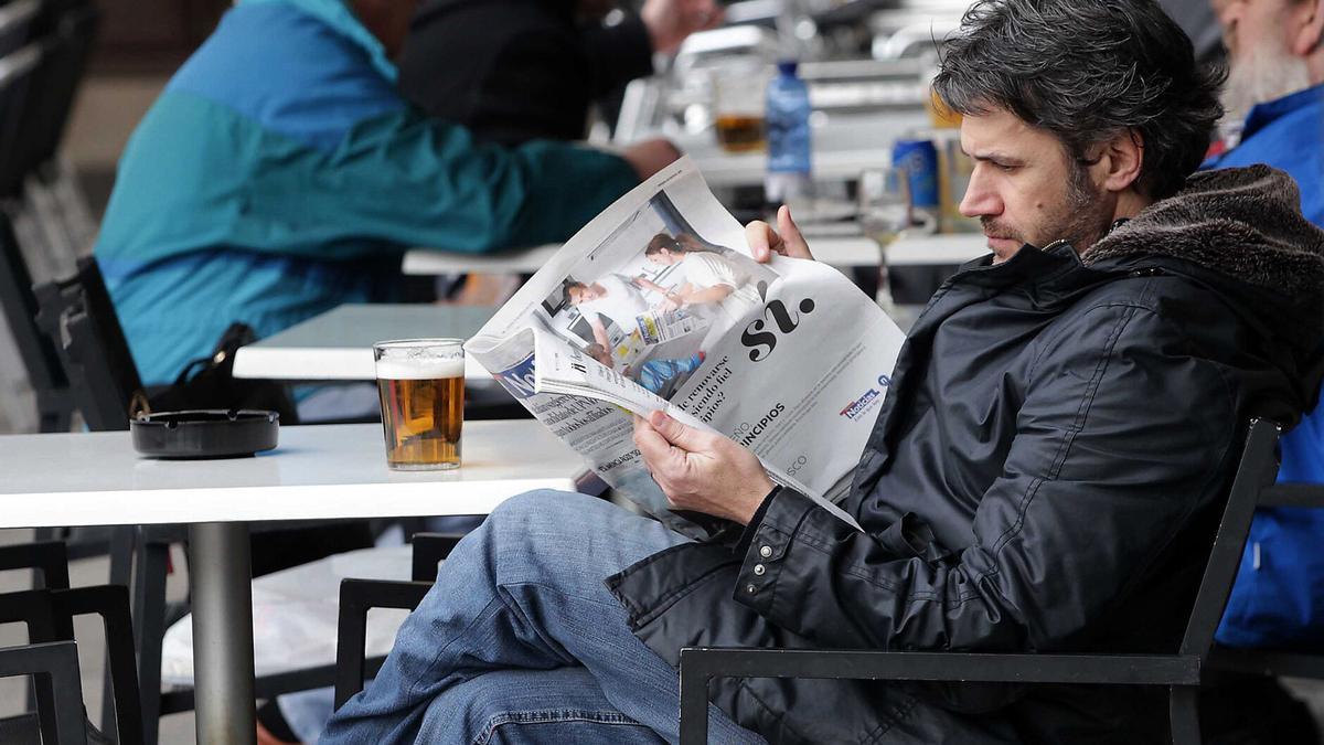 Un hombre lee DIARIO DE NOTICIAS en una terraza.
