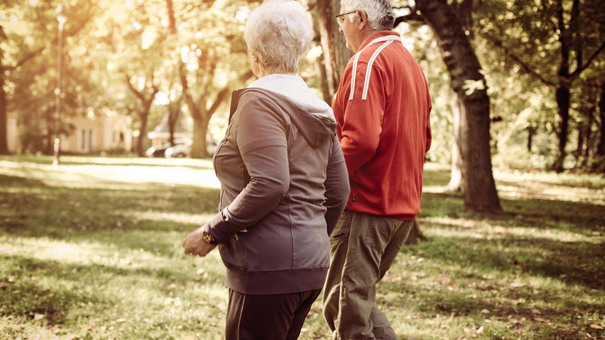 Una pareja mayor caminando por un parque.