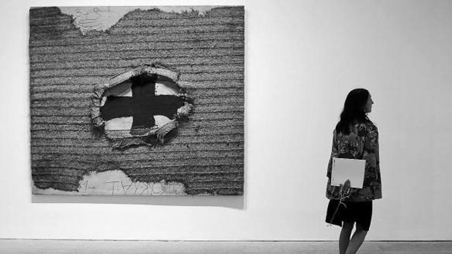 Una mujer pasa ante la obra Estora (1994), pintura y collage sobre madera de Antoni Tàpies.